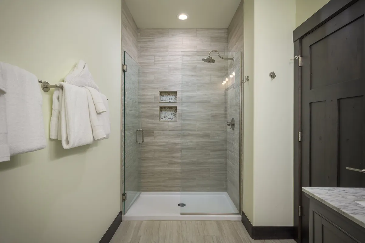A spa-like bathroom highlighted by a glass shower enclosure, marble countertop, textured wall tiles, and fluffy white towels. The design feels elegant and rejuvenating.
