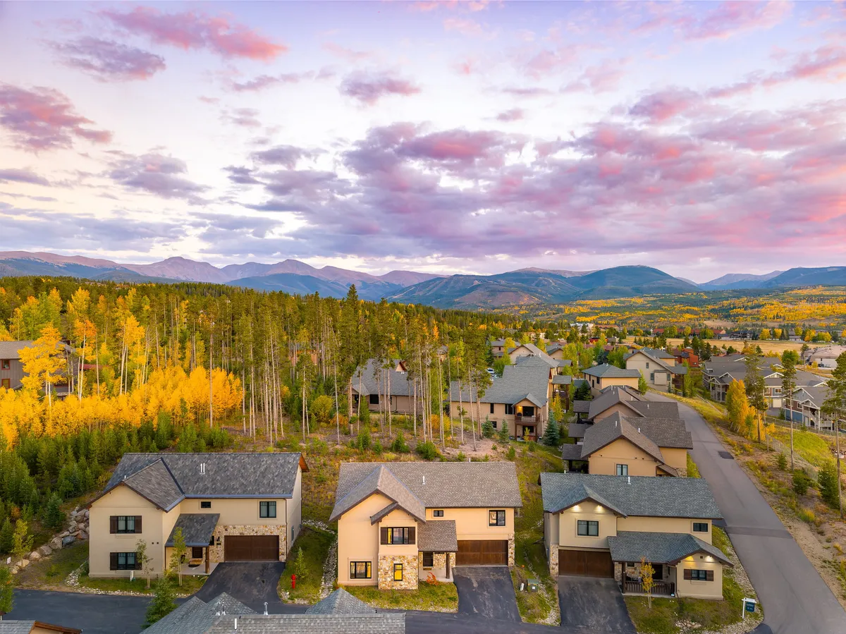 This view image highlights colorful autumn foliage and a breathtaking mountain backdrop, with hints of residential architecture blending into the landscape. The natural scenery evokes the peaceful mountain setting and the promise of memorable sunsets and outdoor activities.