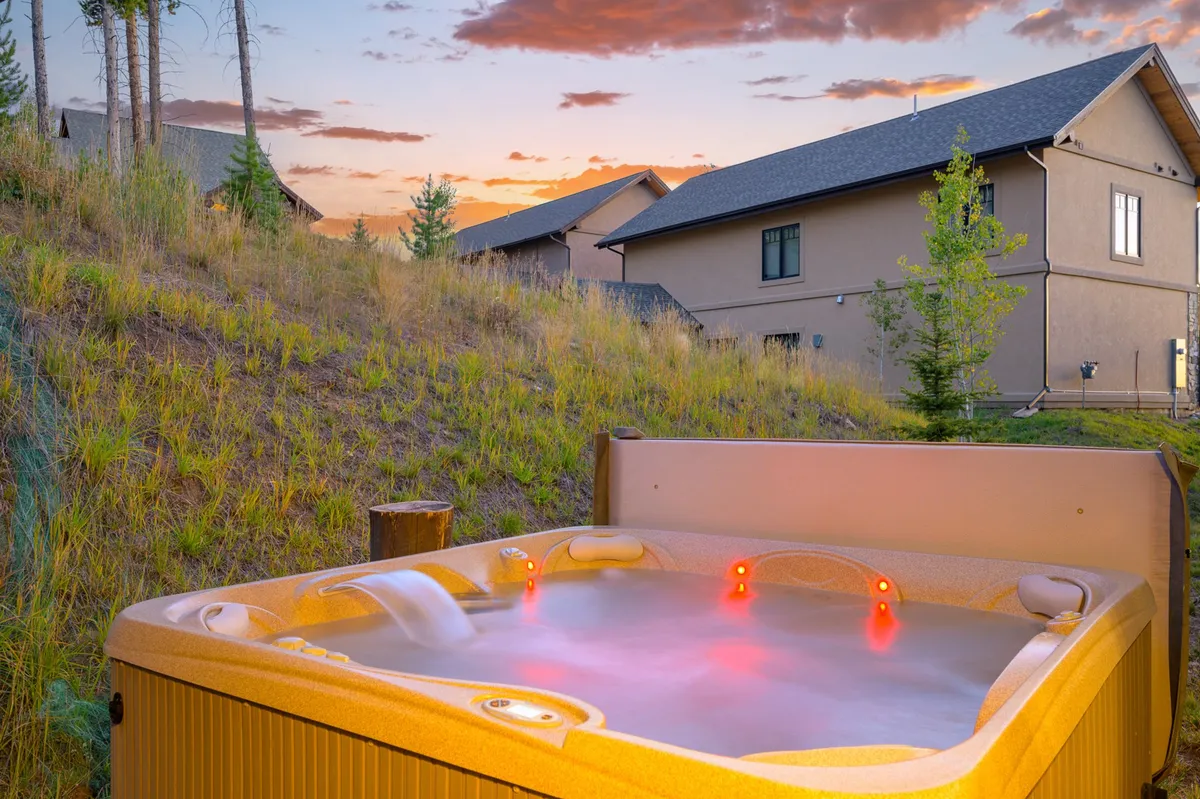 This shot captures a private hot tub with expansive mountain views, set in the home’s outdoor area. The setting is peaceful, with the inviting water suggesting relaxation after a day of exploring, and surrounding homes reinforcing a sense of community.