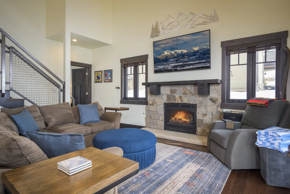 A welcoming living area featuring a central fireplace, a large television, comfortable sofa and armchair, and a coffee table. The space is arranged for relaxation, movie nights, and family gatherings, with decor that feels both homey and elegant.